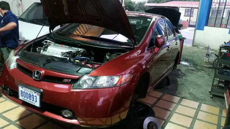 Honda Civic rojo con el capó abierto y un técnico al lado